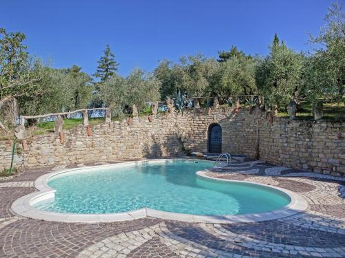 a swimming pool with a stone wall and a brick wall at Apartment in quiet and green environment with swimming pool in Modigliana