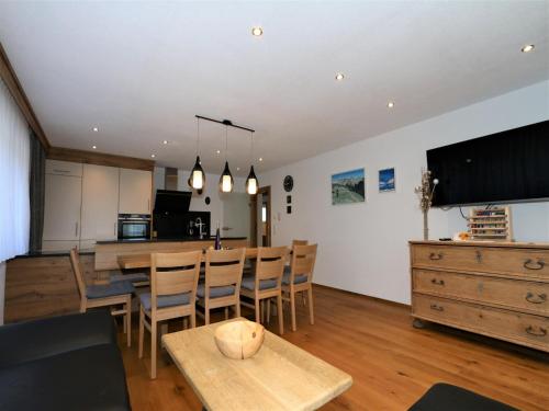 a living room with a table and chairs and a kitchen at High-quality holiday apartment in Oberkrimml near waterfalls in Krimml