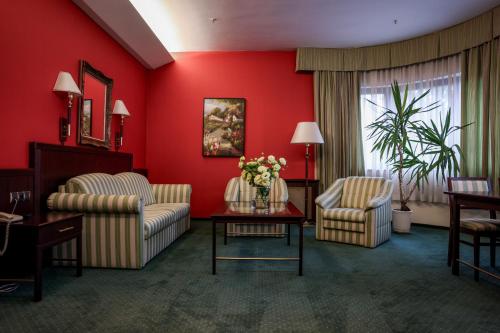 a living room with red walls and chairs and a table at Park Hotel Diament Bielsko-Biała in Bielsko-Biala