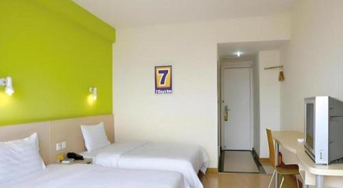 a hotel room with two beds and a television at 7 Days Inn Guangzhou Zoo Huanghuagang Metro Station in Guangzhou