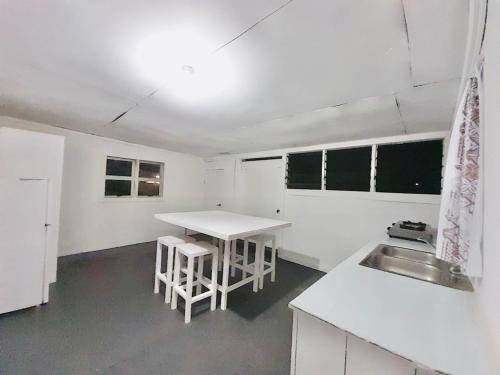 a white kitchen with a sink and a table at Private Double Room - Airport Cottage in Fua‘amotu