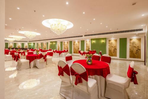 a banquet hall with red and white tables and chairs at Saltstayz Premier - Manesar & Sector 86 in Gurgaon