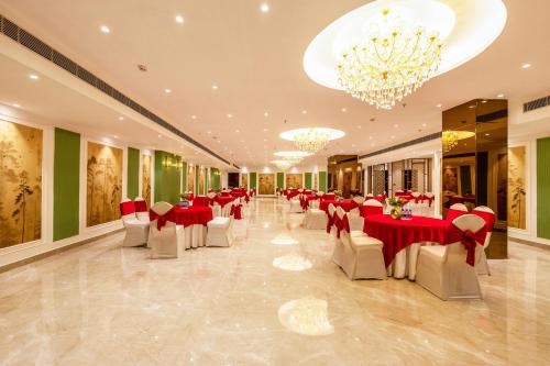 a banquet hall with red tables and white chairs at Saltstayz Premier - Manesar & Sector 86 in Gurgaon