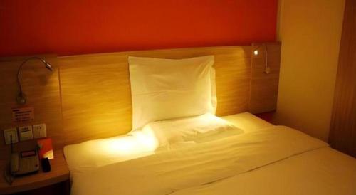 a bedroom with a white bed with a wooden headboard at 7 Days Inn Changchun Zhengyang Street Changchun Park Branch in Changchun