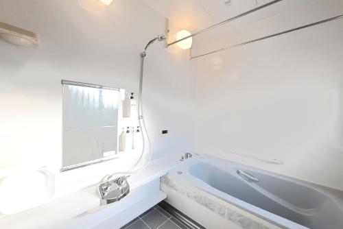 a white bathroom with a tub and a window at 稲穂ゆれる風景と和の趣を味わう 一棟貸し いな穂の宿 和ひかり 
