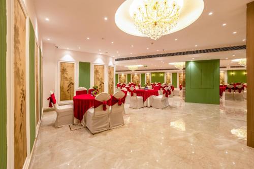 a banquet hall with tables and chairs and a chandelier at Saltstayz Premier - Manesar & Sector 86 in Gurgaon