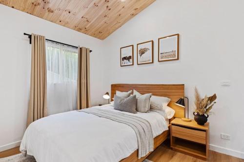 a white bedroom with a bed and a window at Sol Yarra Valley Barrel Sauna & Spa - Urban List in Yarra Glen