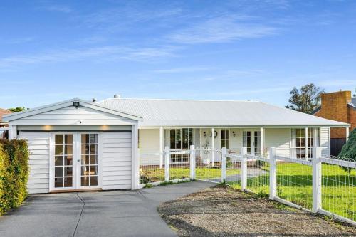 a white house with a fence in front of it at Sol Yarra Valley Barrel Sauna & Spa - Urban List in Yarra Glen