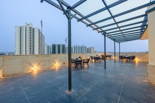a rooftop patio with tables and chairs and buildings at Saltstayz Premier - Manesar & Sector 86 in Gurgaon