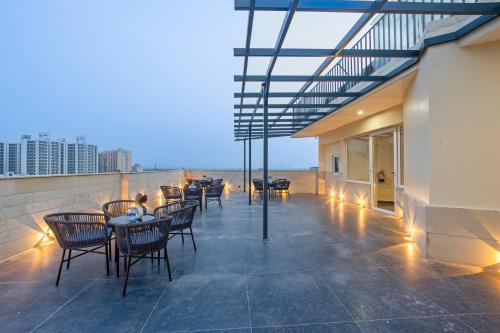 a patio with tables and chairs on the roof of a building at Saltstayz Premier - Manesar & Sector 86 in Gurgaon