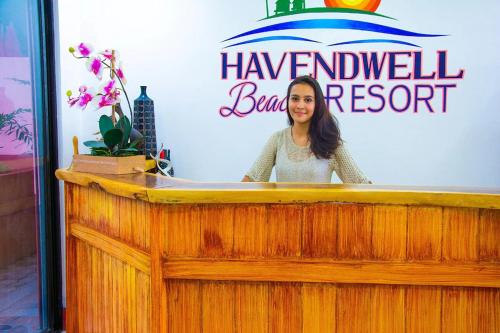 a woman standing behind a podium in front of a sign at Havendwell Beach Resort in Mambajao