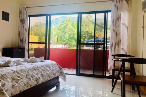 a bedroom with a bed and a large window at Havendwell Beach Resort in Mambajao