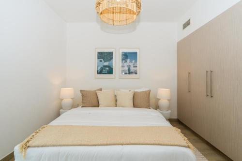 a white bedroom with a large bed with two lamps at One Bedroom Apartment by Otolo Homes with Free Yas Theme Park Tickets in Abu Dhabi
