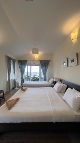 a large white bed in a bedroom with a window at Sunset Villa in Coonoor