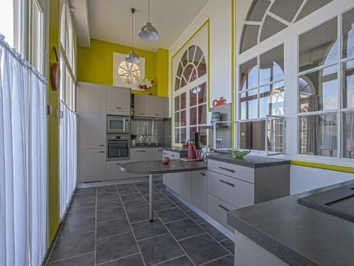 d'une cuisine avec des placards blancs et des murs jaunes. dans l'établissement Spacious holiday home in Aure sur Mer with garden, à Sainte-Honorine-des-Pertes