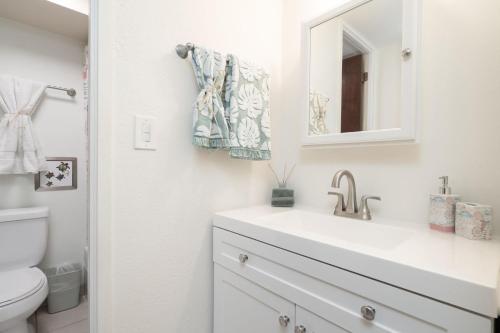a white bathroom with a sink and a mirror at Oceanfront Oasis - Calm Beach - Pool - AC in Hauula