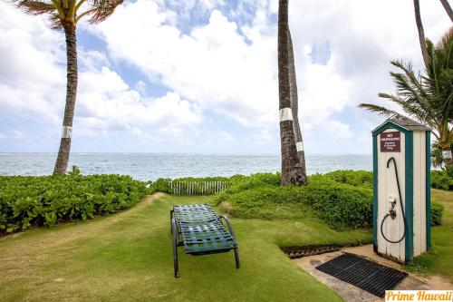 a bench sitting on the grass near the ocean at Oceanfront Oasis - Calm Beach - Pool - AC in Hauula
