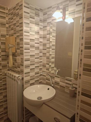 Un baño con un lavabo blanco y un espejo. en B&B Flora, en Aradeo