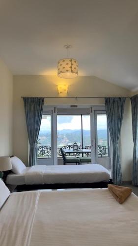 a bedroom with two beds and a balcony at Sunset Villa in Coonoor