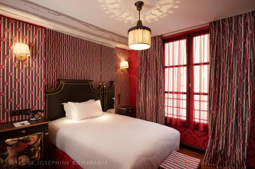 a bedroom with a large bed and red wallpaper at Hôtel de Joséphine BONAPARTE in Paris