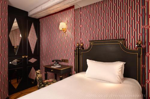 a bedroom with a bed and a red and white wallpaper at Hôtel de Joséphine BONAPARTE in Paris