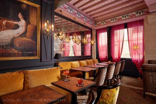 a restaurant with tables and chairs and a couch at Hôtel de Joséphine BONAPARTE in Paris