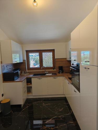 a kitchen with white cabinets and a sink and windows at Villa Niko in Porat