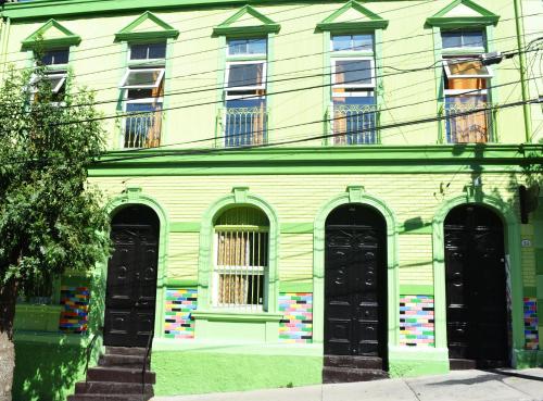 um edifício verde com portas e janelas pretas em La Casa Piola em Valparaíso