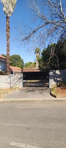 a gate on a house with a tree and a street at 46 On Aries Studio Apartment in Northwold
