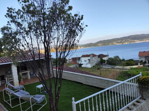 a balcony with two chairs and a tree and the water at Casa PEPE in Combarro