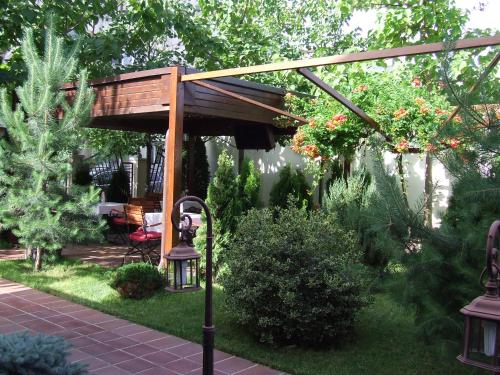 a wooden pergola with a table and chairs in a garden at Hotel Senator in Slatina