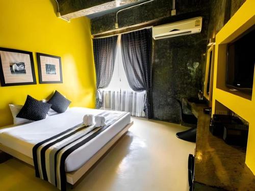 a bedroom with a bed and a yellow wall at The B Ranong Trend Hotel in Ranong