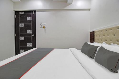 a bedroom with a white bed and a black door at Hotel O Raj Mahal in Turambhe