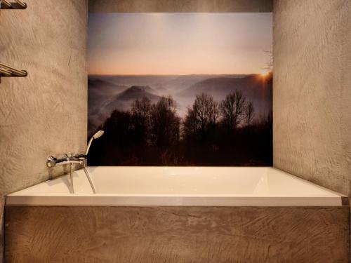 a bath tub with a picture of a mountain view at Fancy Holiday Home in Sainte-Cécile with Pool House & Indoor Pool in Sainte-Cécile