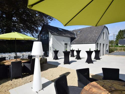 a patio with tables and chairs and a yellow umbrella at Fancy Holiday Home in Sainte-Cécile with Pool House & Indoor Pool in Sainte-Cécile