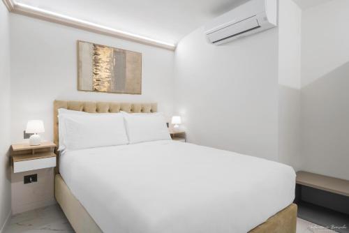 a white bedroom with a bed and two night stands at Hotel Adamas in Florence