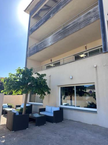 a building with chairs and a tree in front of it at Hôtel A Madonetta in Bonifacio