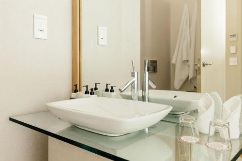 a white bathroom with a sink and a mirror at Oude Werf Hotel in Stellenbosch