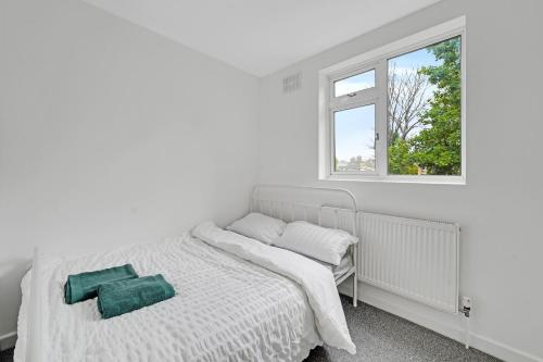 a white bedroom with a bed and a window at London Home with Garden and Parking near Stratford Station in London