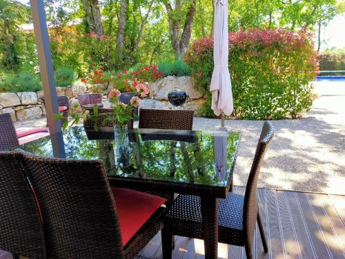 a glass table with chairs and an umbrella on a patio at Modern Villa with Pool in Montauroux France in Montauroux