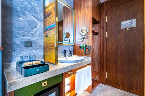a bathroom with a sink and a mirror at Nostalgia S Hotel Kunming Old Street 时光漫步S酒店 昆明火车北站穿心鼓楼地铁站店 Free fresh ground coffee,Free laundry service in Kunming