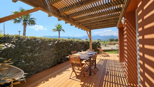 una terrazza in legno con tavolo e sedie sotto un pergolato in legno di Casa Fadiju a Lecci