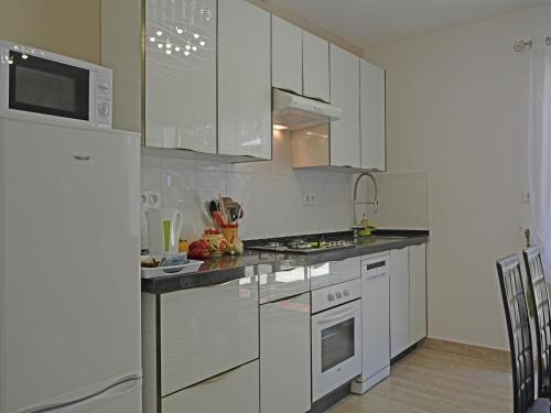 a kitchen with white cabinets and a white refrigerator at Modern Villa with Pool in Montauroux France in Montauroux