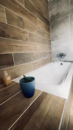 une salle de bain avec une baignoire blanche avec un pot bleu dans l'établissement Superbe villa climatisée, à Connaux