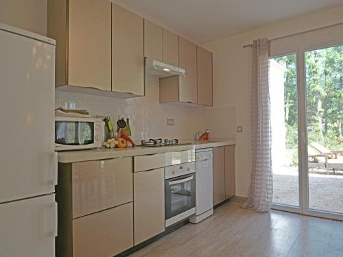 a kitchen with white cabinets and a refrigerator at Modern Villa with Pool in Montauroux France in Montauroux