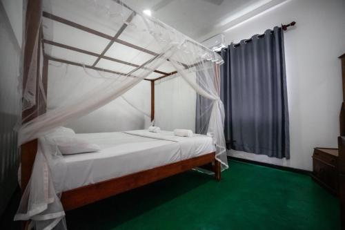 a bedroom with a bed with a canopy at Why Not Hostel in Mirissa