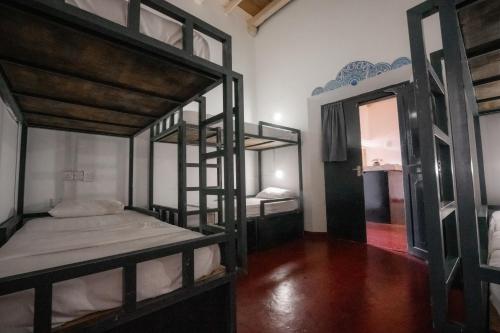a room with three bunk beds and a mirror at Why Not Hostel in Mirissa