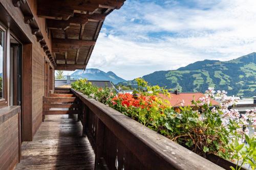 a balcony with flowers and a view of mountains at Pension Heidelberg in Hopfgarten im Brixental