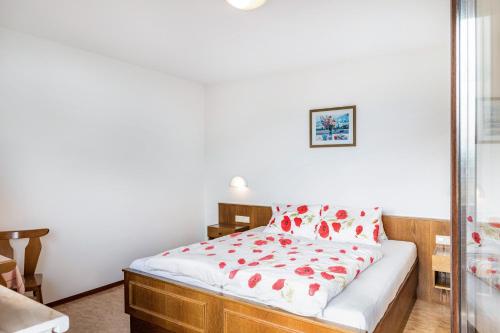 a bedroom with a bed with red flowers on it at Pension Heidelberg in Hopfgarten im Brixental