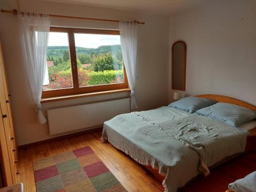 a bedroom with a bed and a large window at Ferienwohnung Hildegard in Ormesheim
